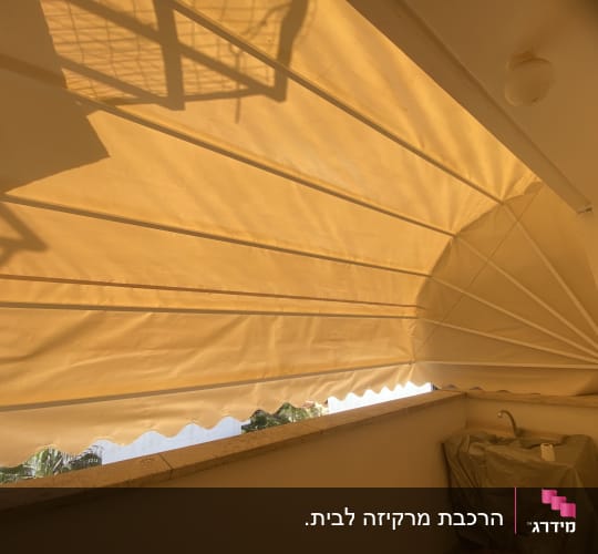 סוכך מרקיזה מתקפל בצבע קרם מותקן במרפסת בית